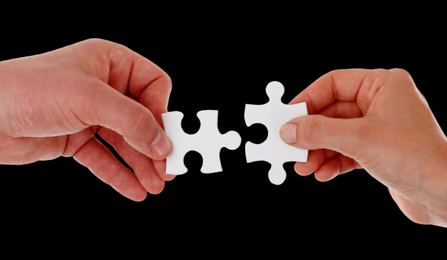 Dłonie trzymające łączące się puzzle